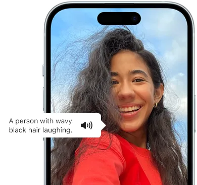 Widoczny na ekranie iPhone’a 15 komunikat VoiceOver z następującym opisem zdjęcia: śmiejąca się osoba z falowanymi czarnymi włosami