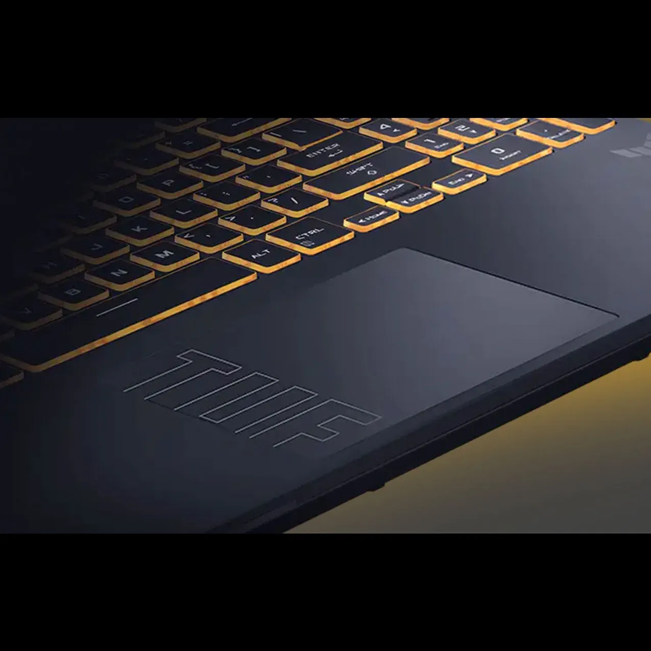 Zbliżenie na klawiaturę laptopa ASUS TUF z żółtym podświetleniem klawiszy oraz dużym touchpadem z wytłoczonym logo TUF.