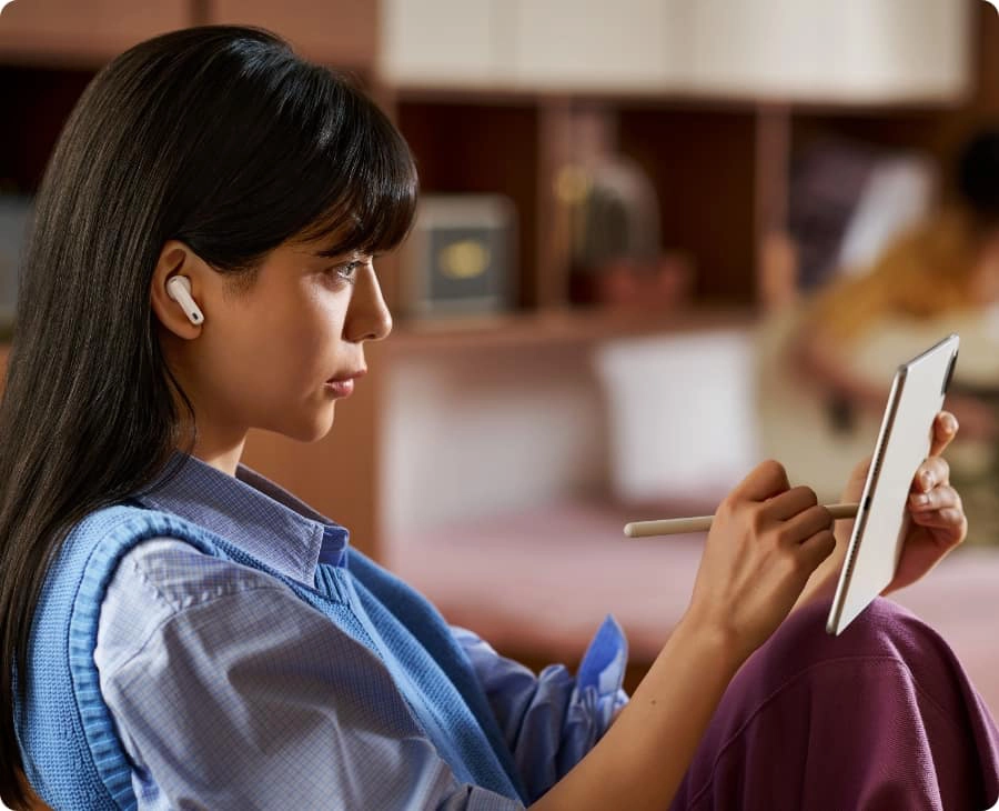 Kobieta używająca słuchawek HUAWEI FreeBuds 7i z tabletem, funkcja adaptacyjnej redukcji szumów
