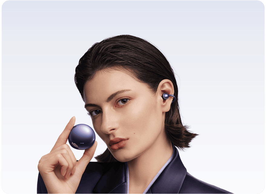 Twarz kobiety z niebieską słuchawką HUAWEI FreeClips 2 S w uchu. W palcach trzyma niebieskie etui ładujące