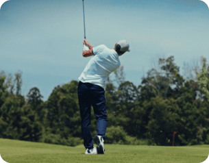 Golfista na polu golfowym tuż po uderzeniu piłki z kijem uniesiony wysoko nad głową
