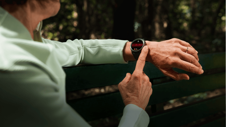 Ekran zegarka HUAWEI Watch Gt Runner 2 na ręku mężczyzny w sportowej bluzie, wyświetla czerwony liniowy wykres i ikonę serca
