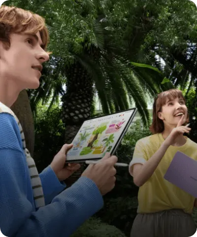Młodzi ludzie w ogrodzie botanicznym oglądający atlas roślin na tablecie