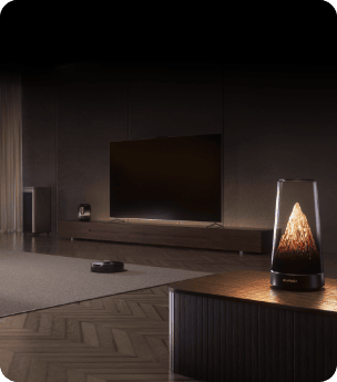 Pokój z drewnianą podłogą, dwiema komodami i płaskim telewizorem. Na pierwszym planie rozświetlony router HUAWEI Mesh X3 Pro.