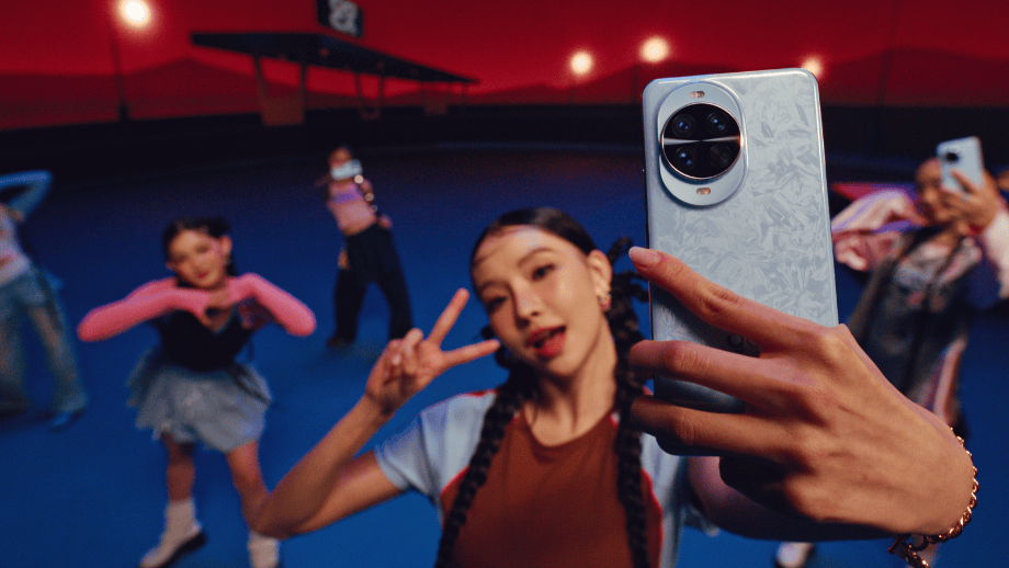 Grupa kolorowo ubranych tancerek pozuje do zdjęcia. Kobieta na pierwszym planie trzyma w ręku smartfon Huawei Nova 14 Pro