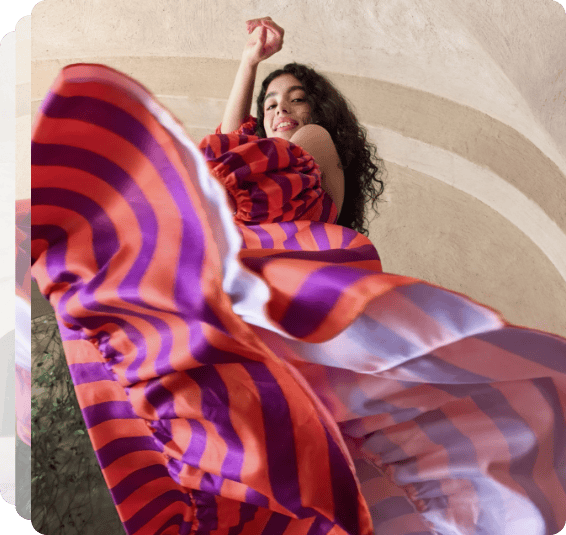 Ciemnowłosa tancerka flamenco, we wzorzystej sukni w trakcie tanecznej figury. W tle łuk sklepienia budynku
