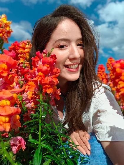 Uśmiechnięta kobieta wśród pomarańczowo-czerwonych kwiatów, zdjęcie portretowe