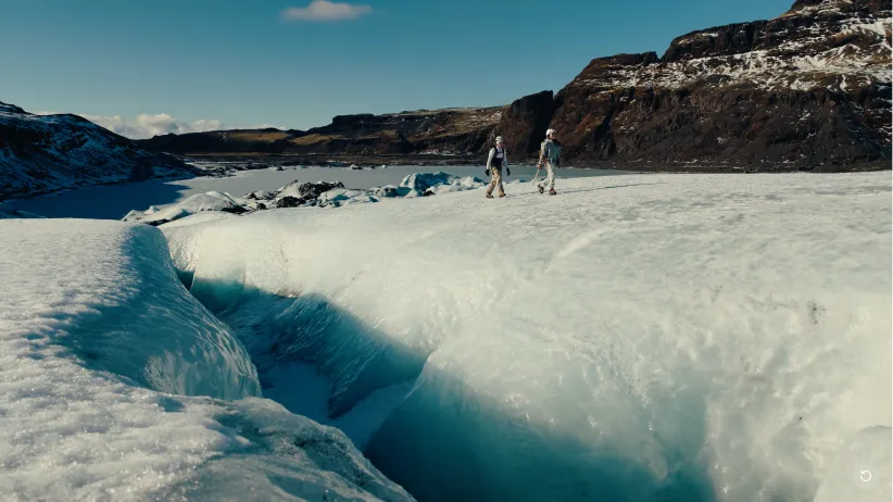 Dwoje turystów spacerujących po lodowcu z pęknięciem i błękitnym lodem na Islandii