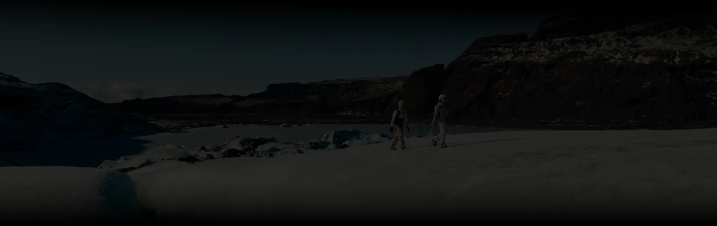 Ciemna panorama z ledwo widocznymi sylwetkami dwóch osób idących po lodowcu nocą