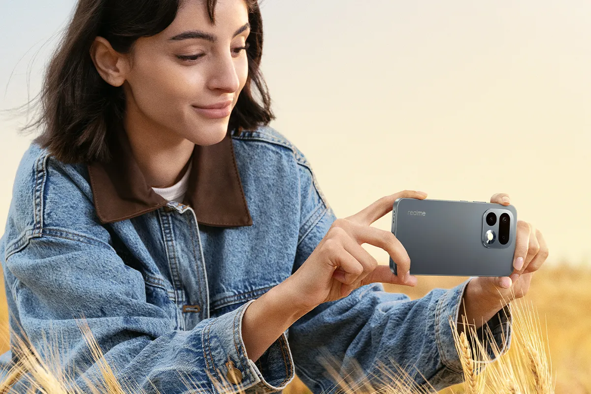 Kobieta robiąca zdjęcie smartfonem realme 16 Pro 5G na tle plenerowym.