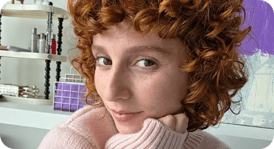 Ujęcie twarzy kobiety z kręconymi włosami w jasnym pomieszczeniu.