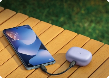 smartfon leżący na stoliku podłączony kablem USB do słuchawek