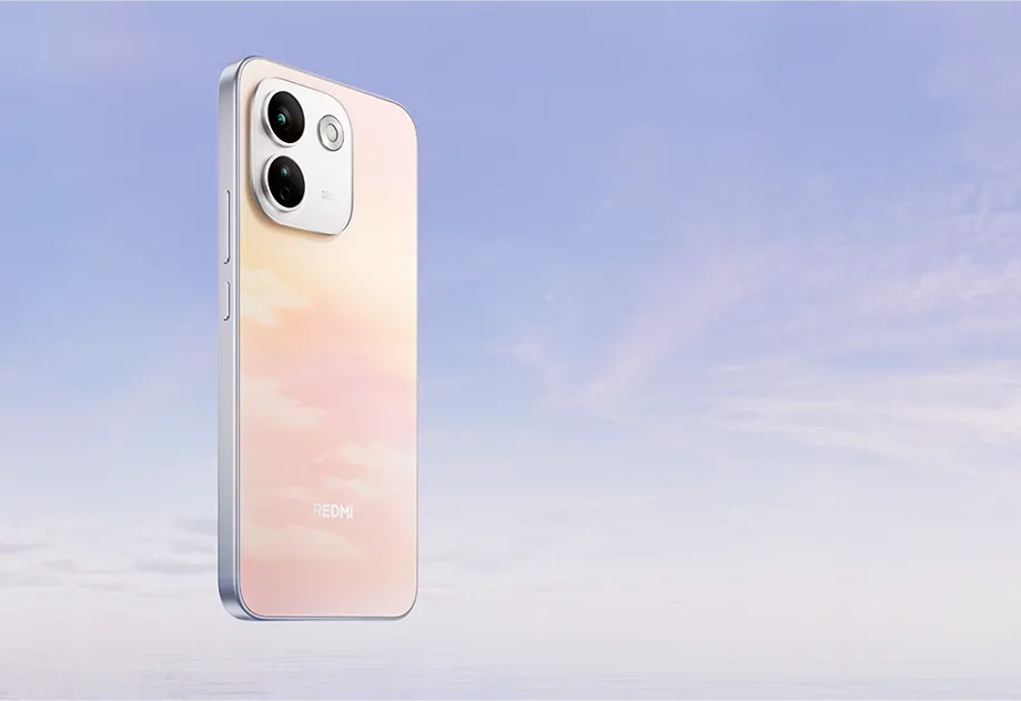 Tył smartfona REDMI w jasnym, pastelowym wykończeniu na tle nieba