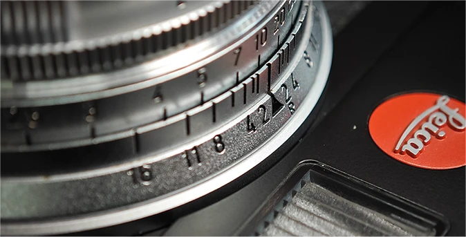 Zbliżenie na pierścień obiektywu Leica z oznaczeniami przysłony
