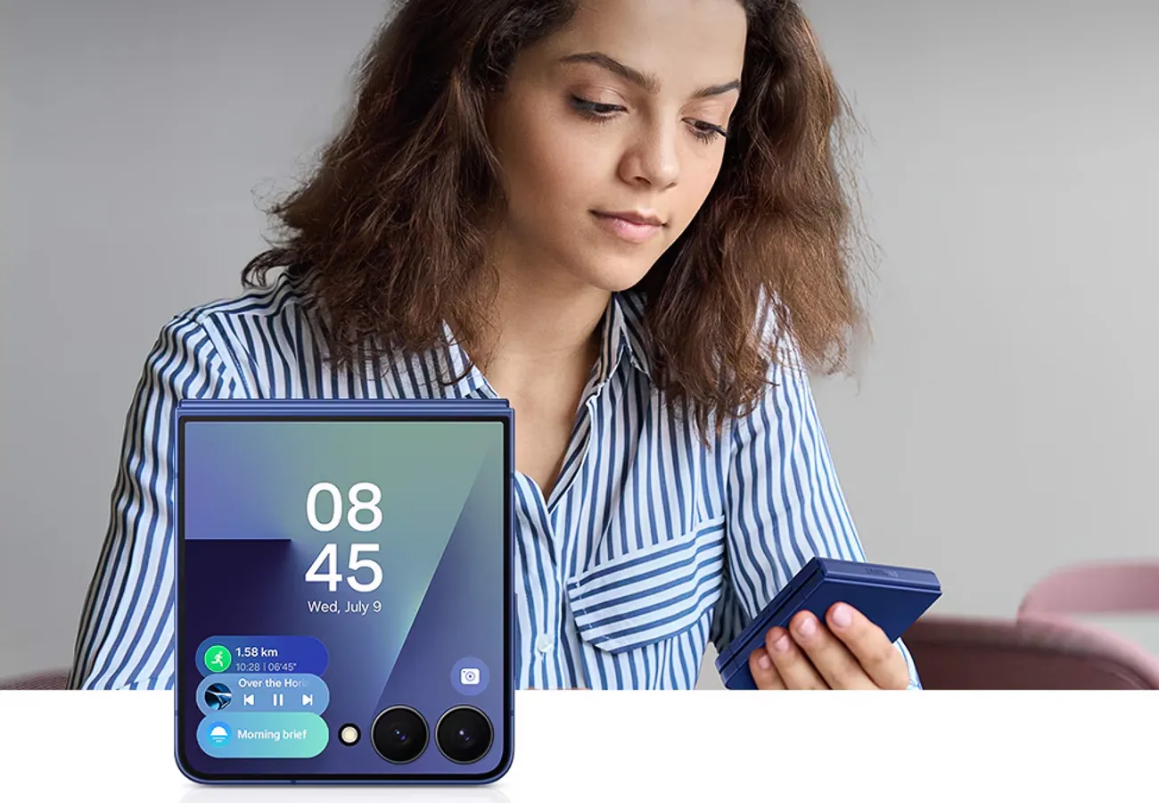 Kobieta siedzi z telefonem, na ekranie widoczny interfejs funkcji Now Bar z godziną, datą i powiadomieniami.