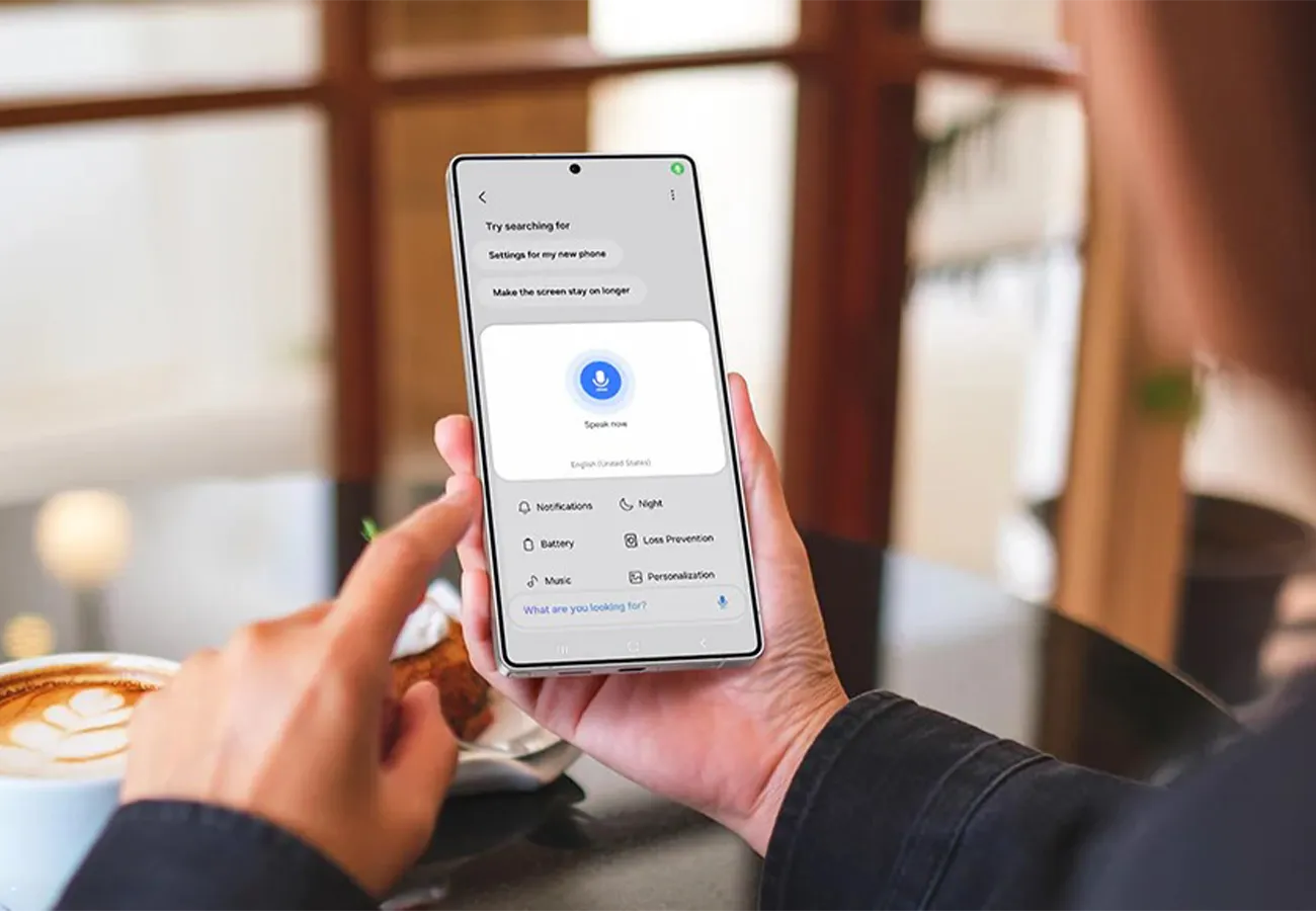 Osoba trzyma smartfon z otwartą funkcją wyszukiwania ustawień Galaxy AI